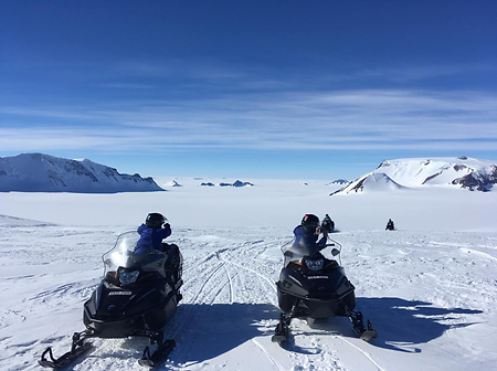 Team members on snowmobiles stopping to take a picture.